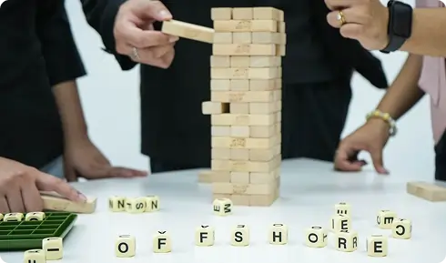 A collaborative team working together on a wooden tower puzzle, symbolising strategic planning and offshore business solutions.